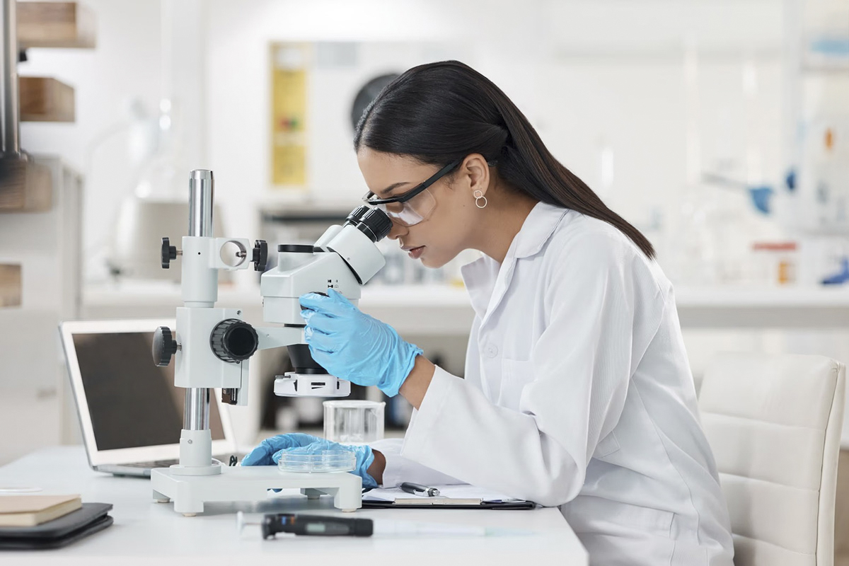 kobieta patrząca przez mikroskop w laboratorium