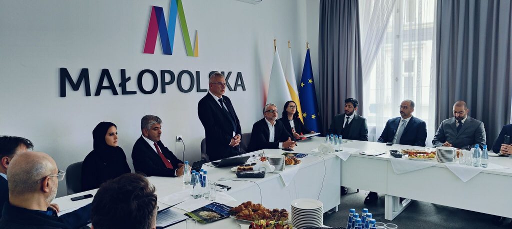 Przemówienie dyrektora Jerzego Kopcia podczas spotkania z delegacją Zjednoczonych Emiratów Arabskich, w tle logo Małopolski i flagi Polski, Małopolski i Unii Europejskiej